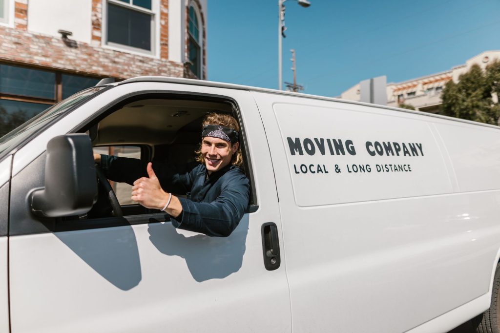 A moving truck from Mayflower Movers parked near a brick building on a sunny day.