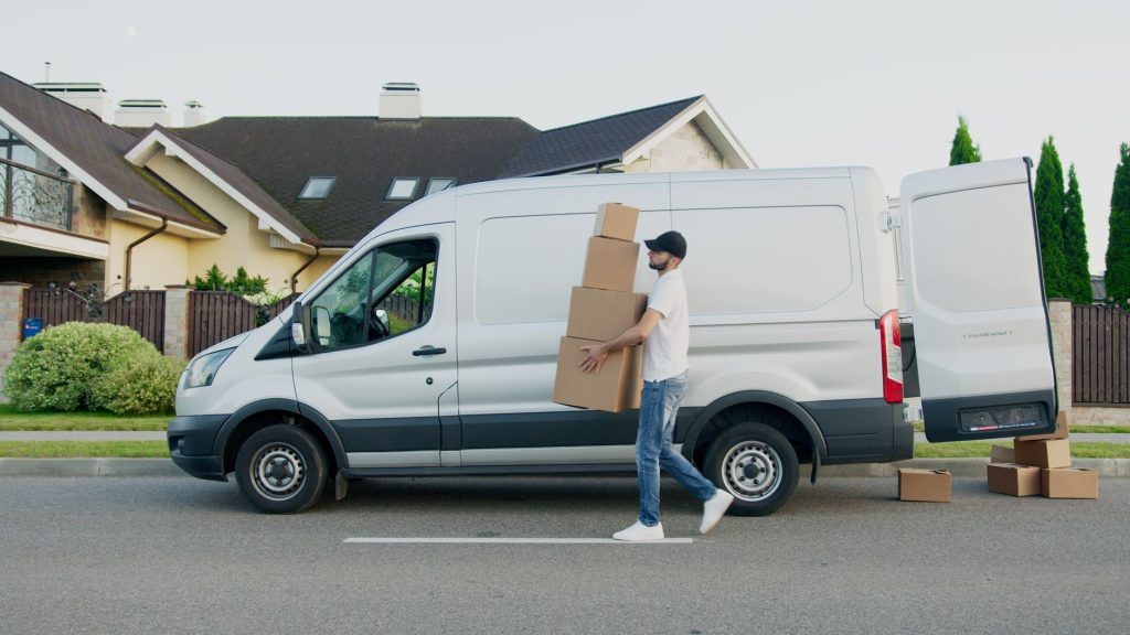 A team of movers loads furniture from a residential truck on Jogoo Road, with stacks of boxes nearby.