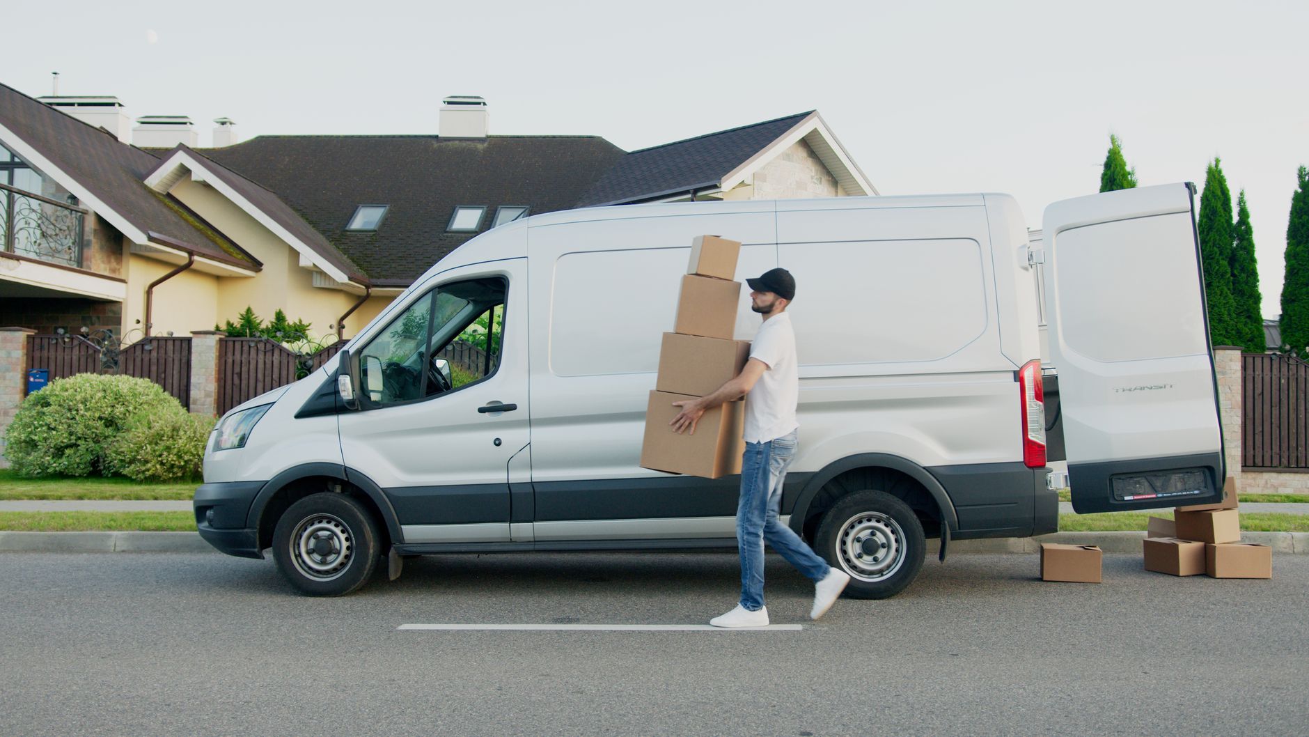 Professional movers in blue uniforms carrying a large cardboard box.